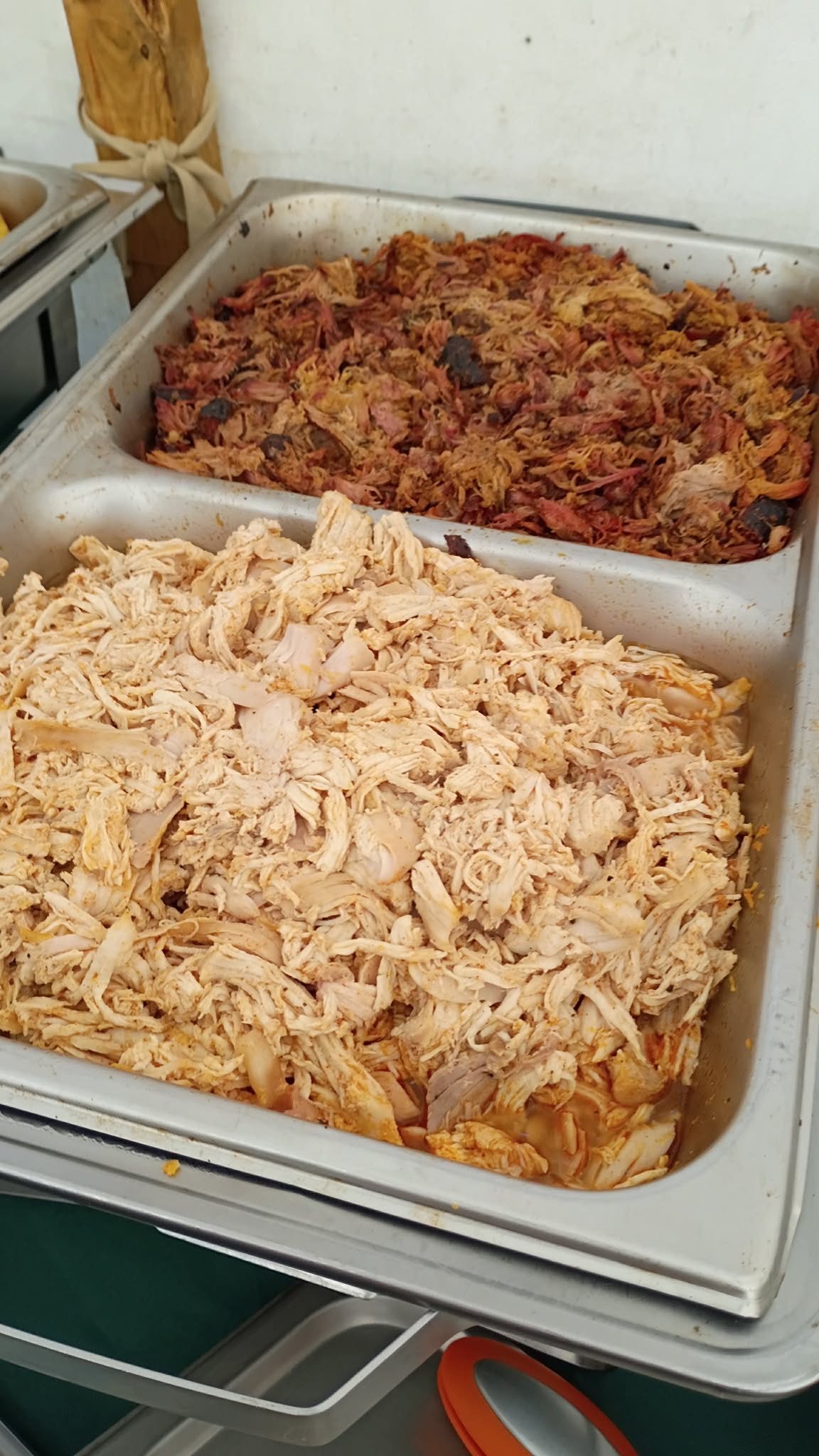 Two chafing dish sections, one of smoky pulled pork and one of shredded seasoned pulled chicken