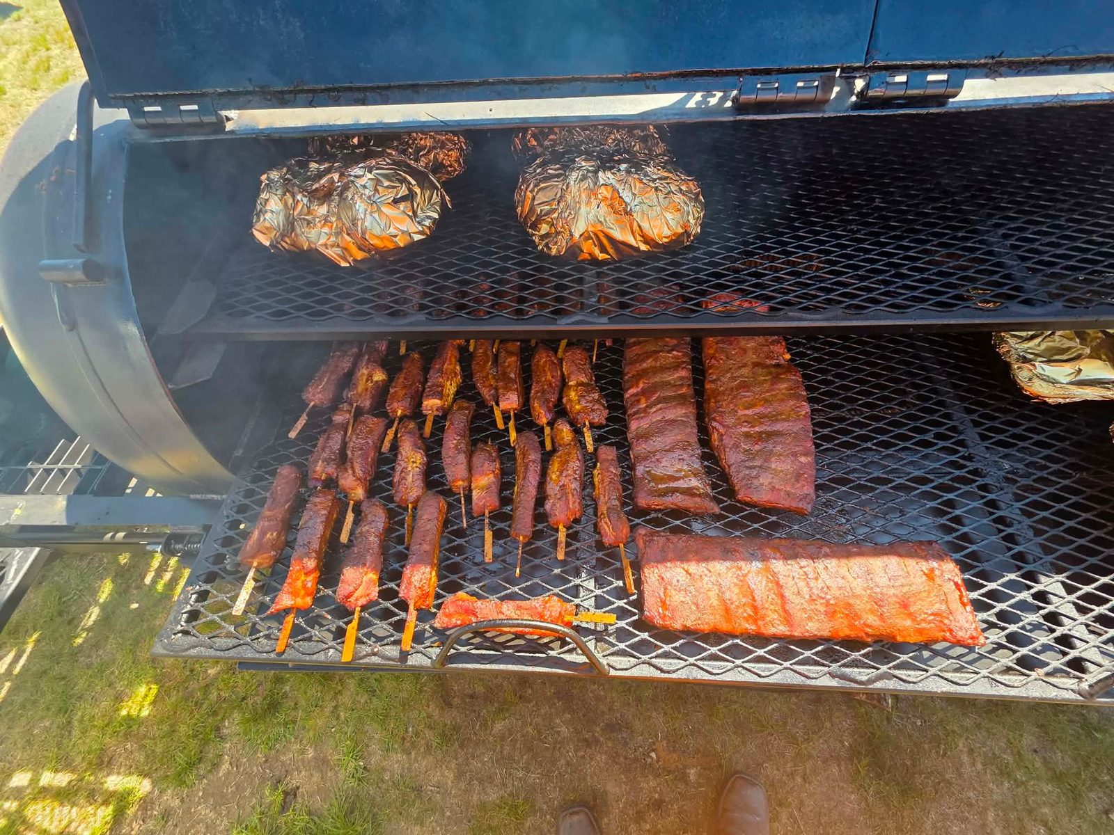 Dragon Tails skewers and racks of ribs on the grates of the Oak & Ash smoker